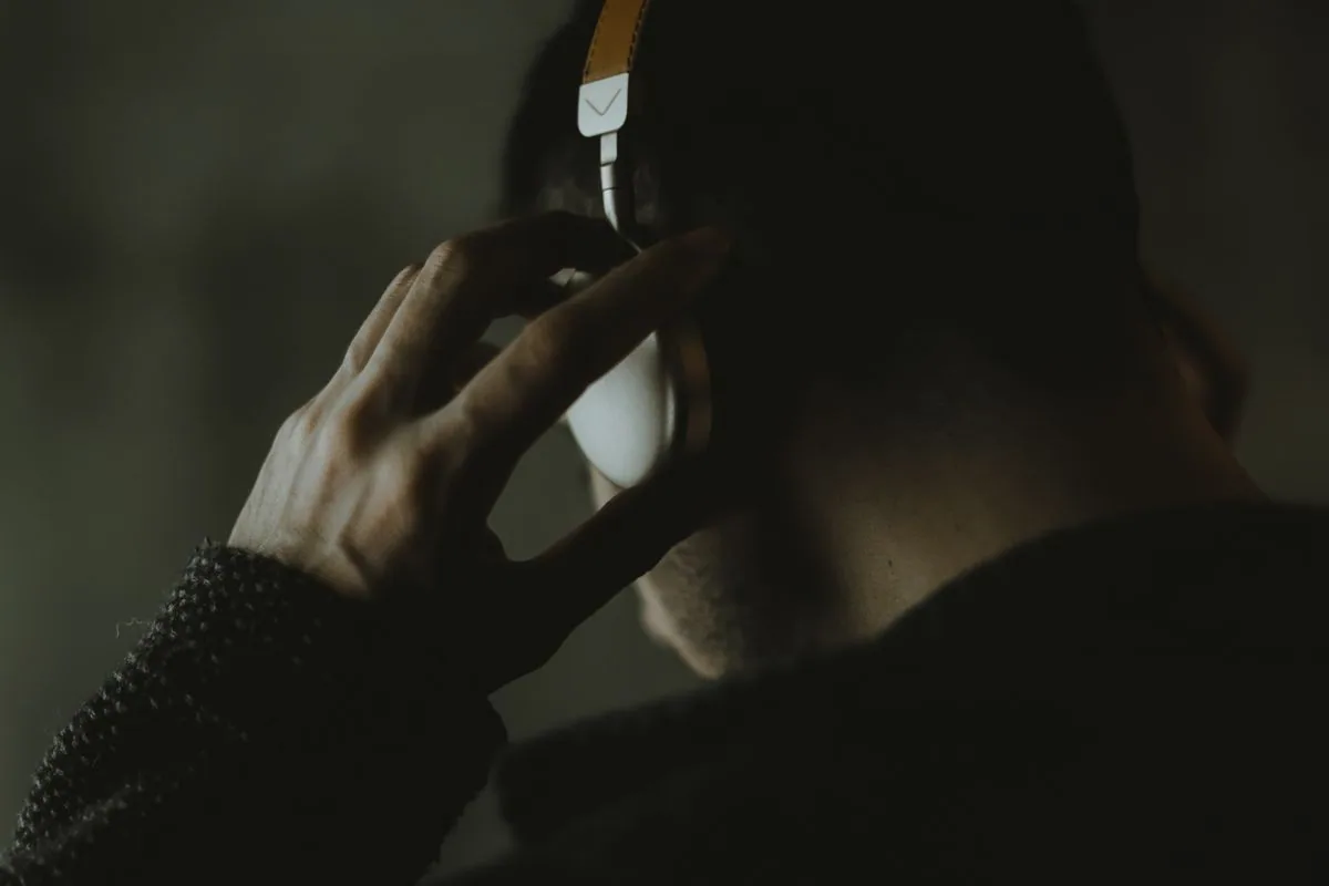 Une personne porte un casque audio dans une ambiance sombre.