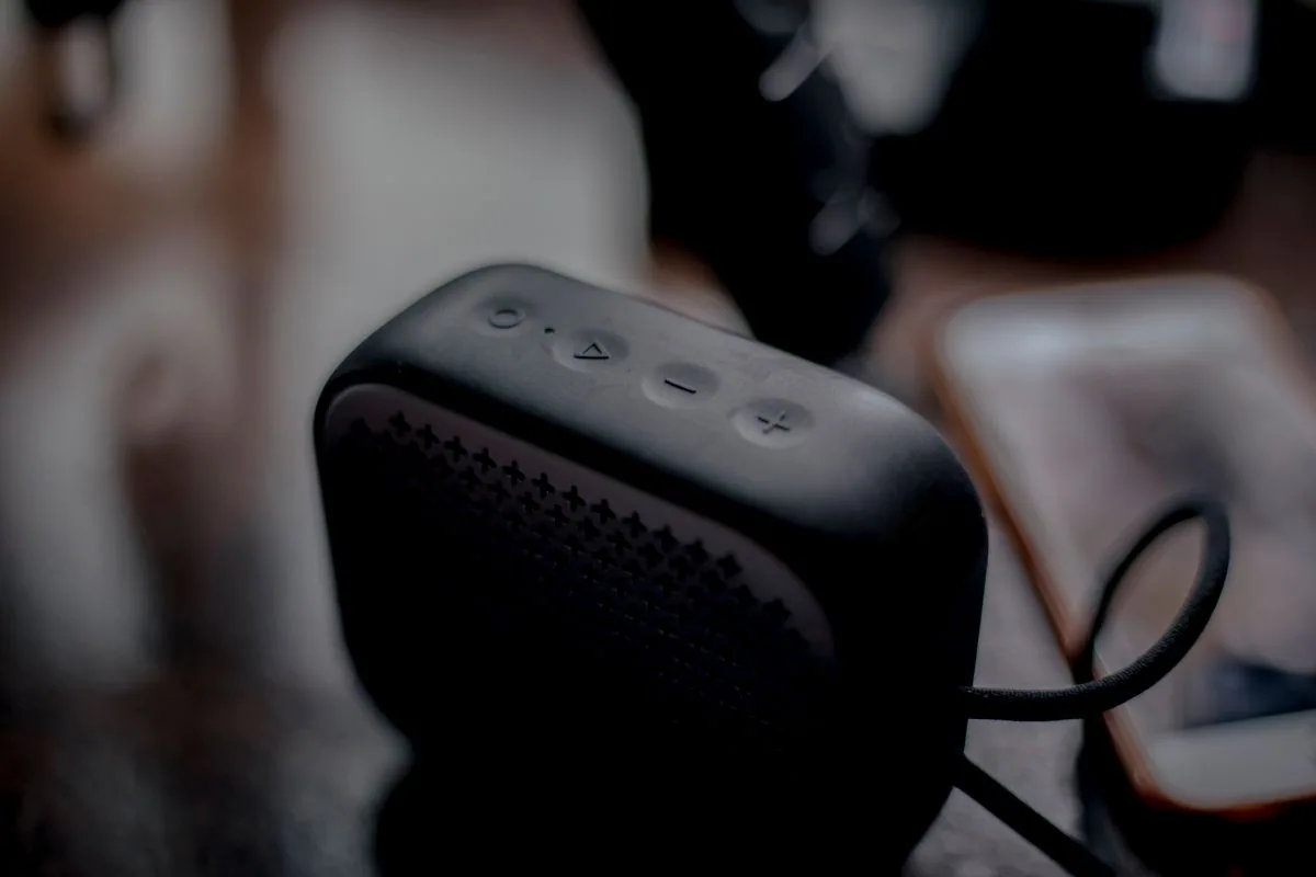 Enceinte Bluetooth portable et téléphone posés sur une table en bois.
